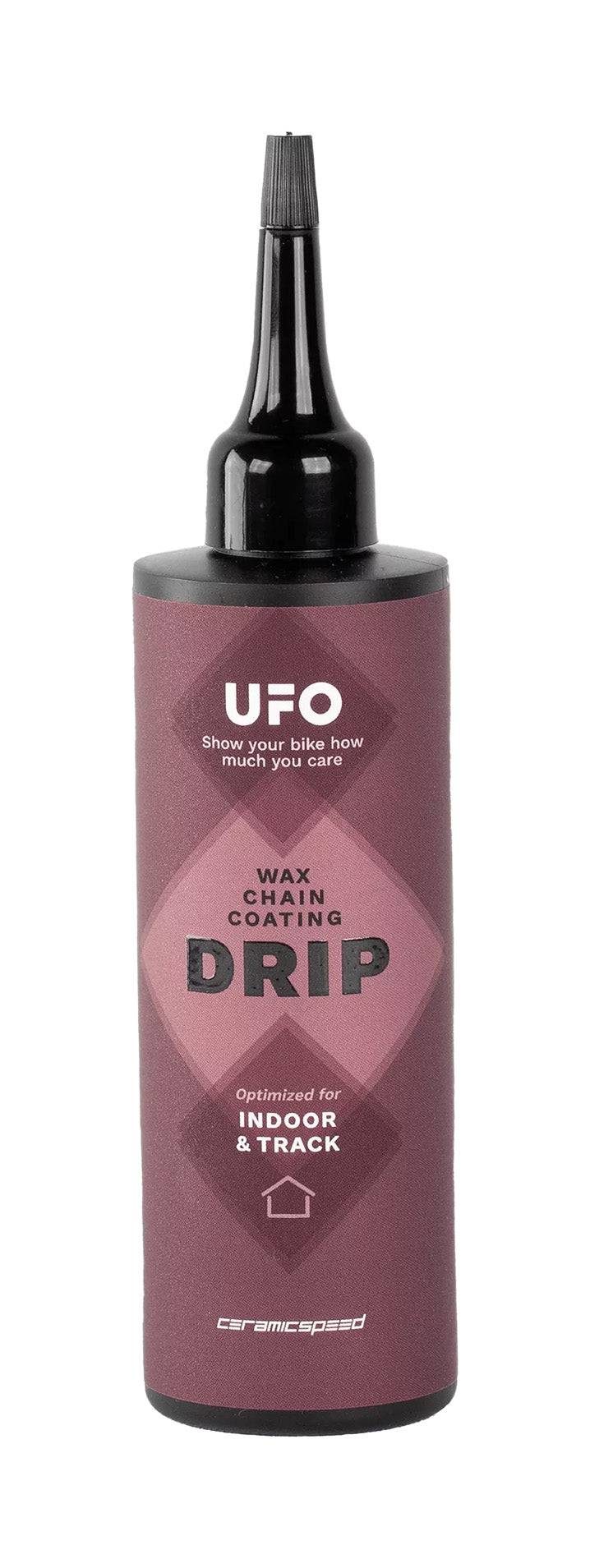 CeramicSpeed UFO Drip indoor chain lubricant in 100ml bottle, designed for wax-coated bicycle chains, shown in workshop setting.
