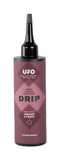 CeramicSpeed UFO Drip indoor chain lubricant in 100ml bottle, designed for wax-coated bicycle chains, shown in workshop setting.