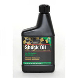 Finish Line Shock Oil 2.5 wt suspension fluid for bicycle forks, shown in 16 oz (475 ml) bottle in a workshop setting.