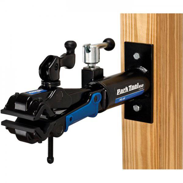 Park Tool PRS-4W-2 Deluxe Wall-Mount Bike Repair Stand with 100-3D Clamp, mounted on workshop wall for bike maintenance.
