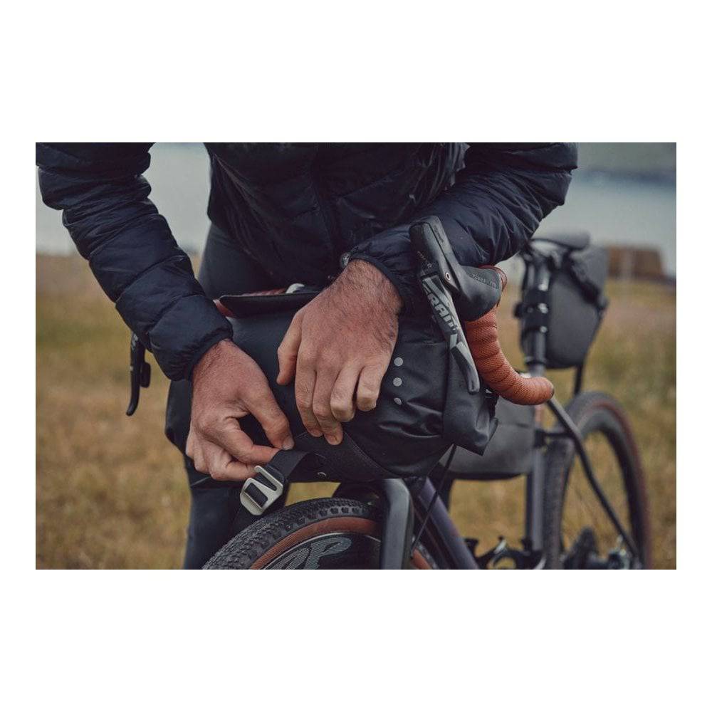 Brooks Scape Handlebar Roll Bag in mud green waterproof bikepacking gear accessory attached to a bike handlebar.