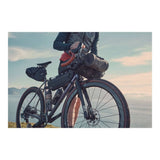 Brooks Scape Handlebar Roll Bag in mud green waterproof bikepacking gear attached to a bike handlebar.