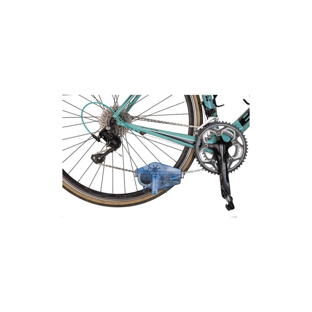 Park Tool CM-5.3 Cyclone chain scrubber for multi-speed bikes and e-bikes, shown in workshop setting with cleaning brushes and tools.