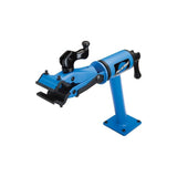 Park Tool PCS-12.2 bike repair stand with micro-adjust clamp mounted on workbench, used for bicycle maintenance and repairs.