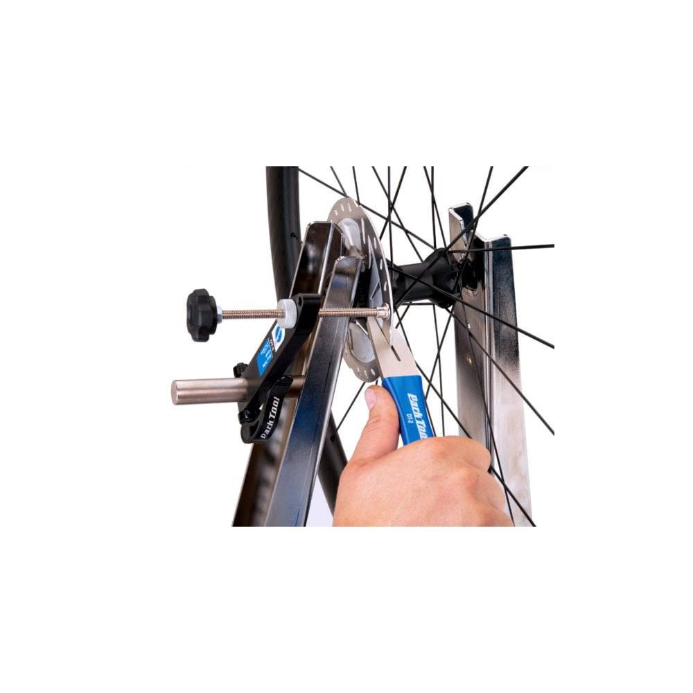 Park Tool DT-2 rotor truing fork for precise disc brake rotor adjustment in a workshop setting.