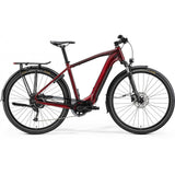 Merida eSpresso 400 S EQ electric hybrid bike with integrated lights, rear rack, and mudguards, parked on a city street.