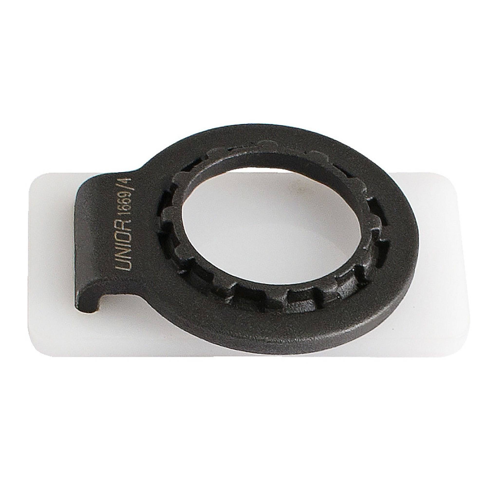 UNIOR 2-in-1 bike spoke and cassette lockring tool for maintenance, shown in a workshop setting with metal tools.