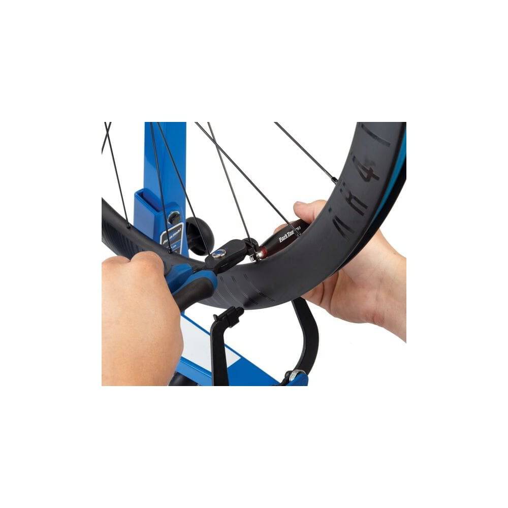Park Tool CSH-1 clamping spoke holder for wheel truing and spoke tensioning in a workshop setting.