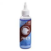 Joe's No Flats PTFE Wet Lube bicycle chain lubricant for wet and muddy conditions, shown in a workshop setting.