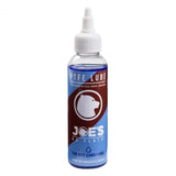 Joe's No Flats PTFE Wet Lube bicycle chain lubricant for wet and muddy conditions, shown in a workshop setting.