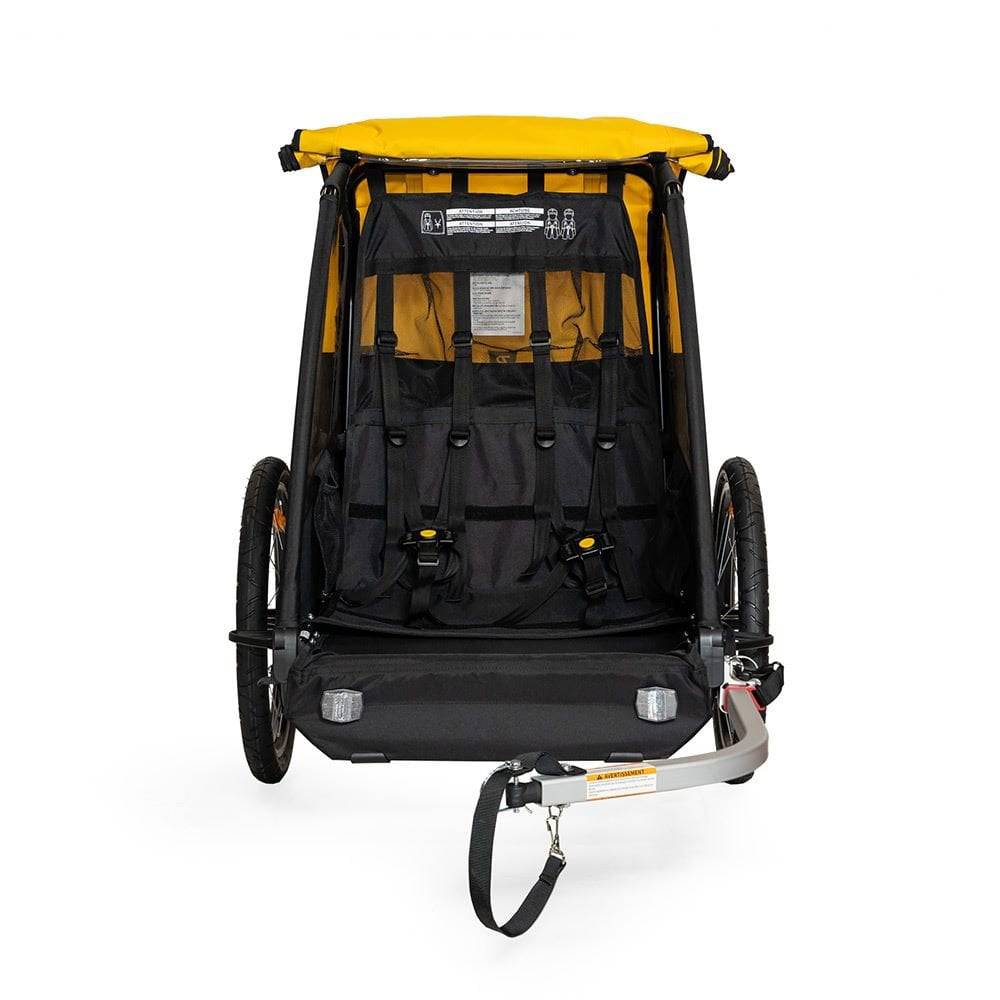Burley Bee bike trailer for kids, showing double-seat with 5-point harness and storage compartments, outdoor riding accessory.