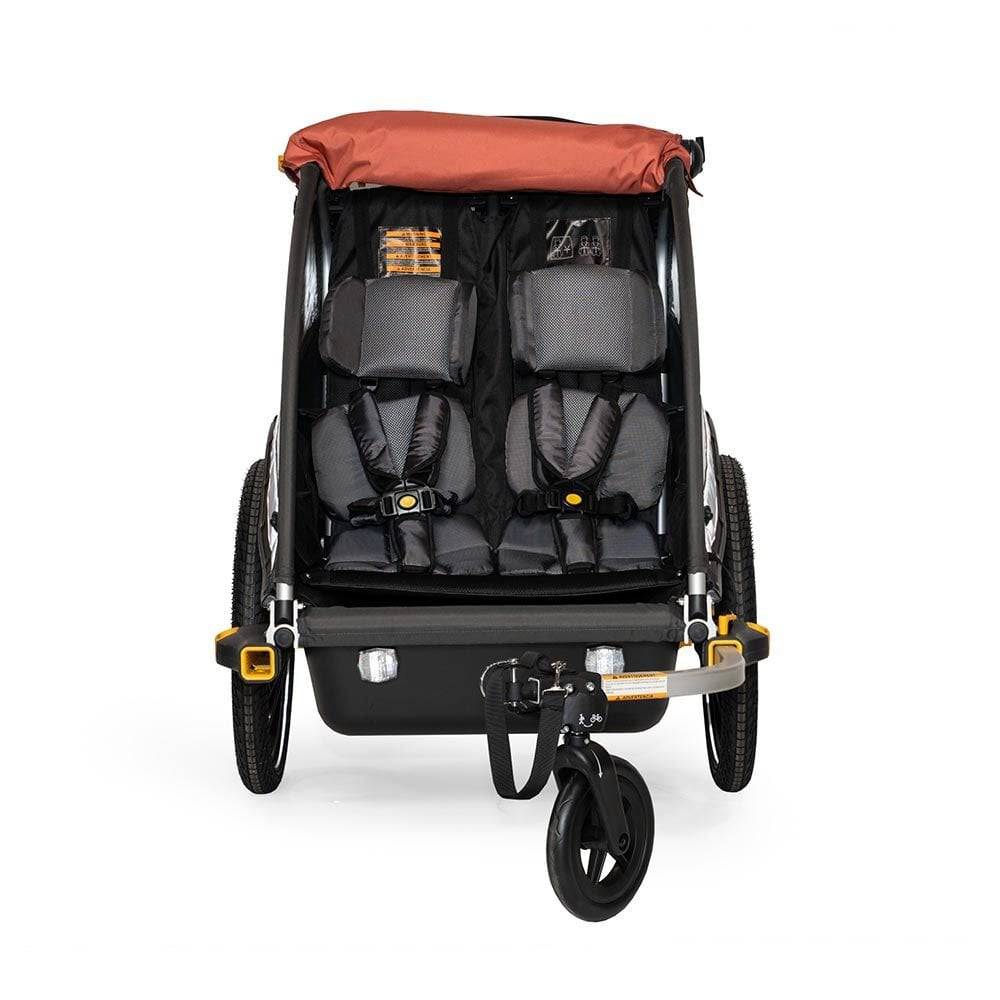 Burley Cub X bike trailer and stroller for all-terrain riding and e-bike compatibility, shown in a vibrant outdoor setting.