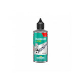 Motorex Chainlube with PTFE, 100ml, synthetic bike chain lubricant for dry conditions, with a workshop setting in the background.
