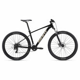 Giant Talon 4 2024 mountain bike with Shimano Tourney gears and disc brakes, black and red frame, outdoor trail setting