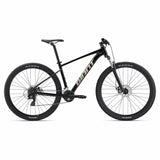 Giant Talon 4 2024 mountain bike with Shimano Tourney gears and disc brakes, black and red frame, outdoor trail setting
