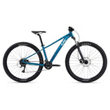 Liv Tempt 3 women’s 2024 mountain bike with Shimano Acera gears and disc brakes, shown in an outdoor mountain trail setting.