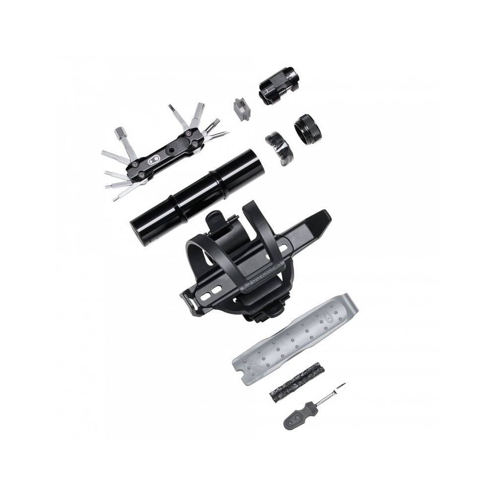 Crankbrothers BC18 SOS Bottle Cage Tool Kit with multi-tool in black and silver, displayed in a workshop setting.