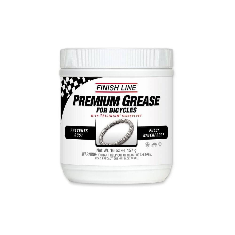 Finish Line Premium Ceramic Tech Grease tube for high-performance bike lubrication, shown in a workshop setting.