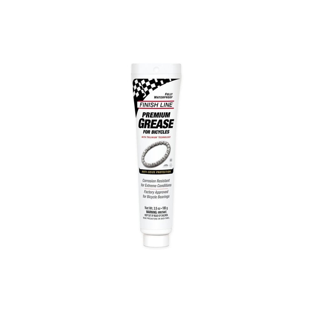 Finish Line Premium Ceramic Tech Grease tube for high-performance bike lubrication, shown in a workshop setting.