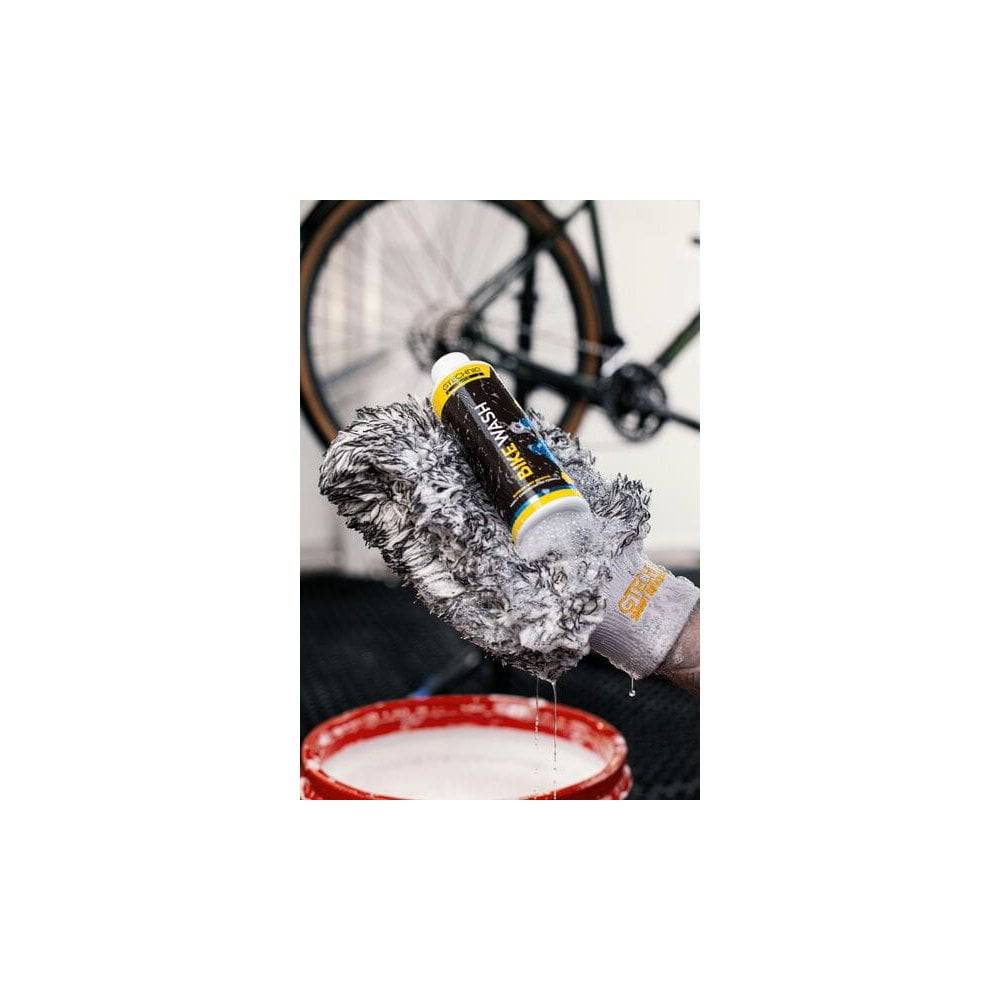 Gtechniq Bike Wash 250ml, pH-neutral biodegradable cleaner for bikes, shown in a workshop setting with cleaning supplies.