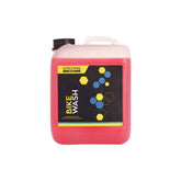 Gtechniq Bike Wash 5L biodegradable pH neutral cleaner in a workshop setting, showing a bottle of bike cleaning solution.