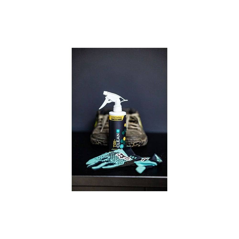 Gtechniq Bike Tri-Clean 500ml antibacterial cleaner for cycling gear and helmets, shown in a workshop setting.