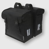 Basil Mara XXL black double bike bag with water-repellent material and reflective strips, mounted on a bicycle pannier rack.