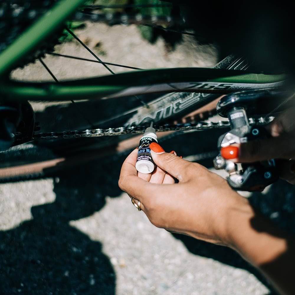 Zefal Extra Wet Ceramic bike chain lubricant bottle for all weather conditions, shown in a workshop setting.
