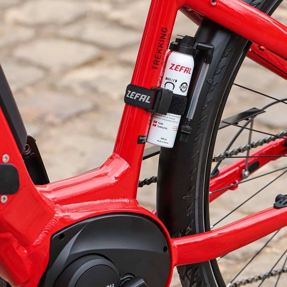 Zefal Puncture Repair Spray for bikes, showing a workshop setting with the spray can and bike tire repair tools.