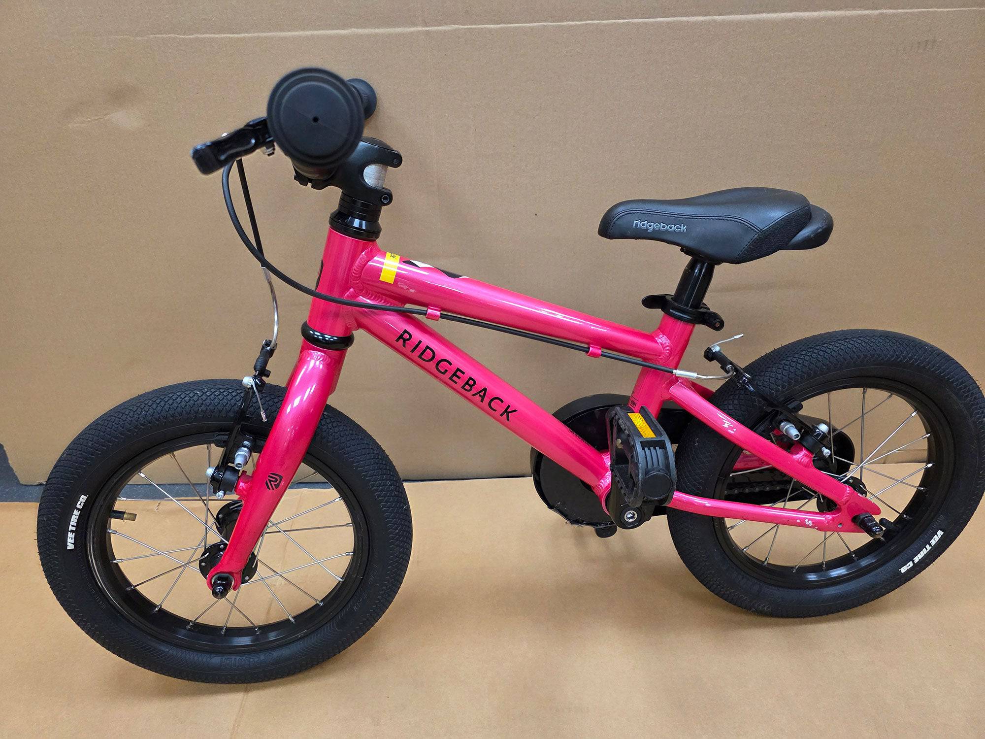 Pink Ridgeback Kids Dimension 14-inch beginner bike with training wheels, ideal for young children learning to ride.