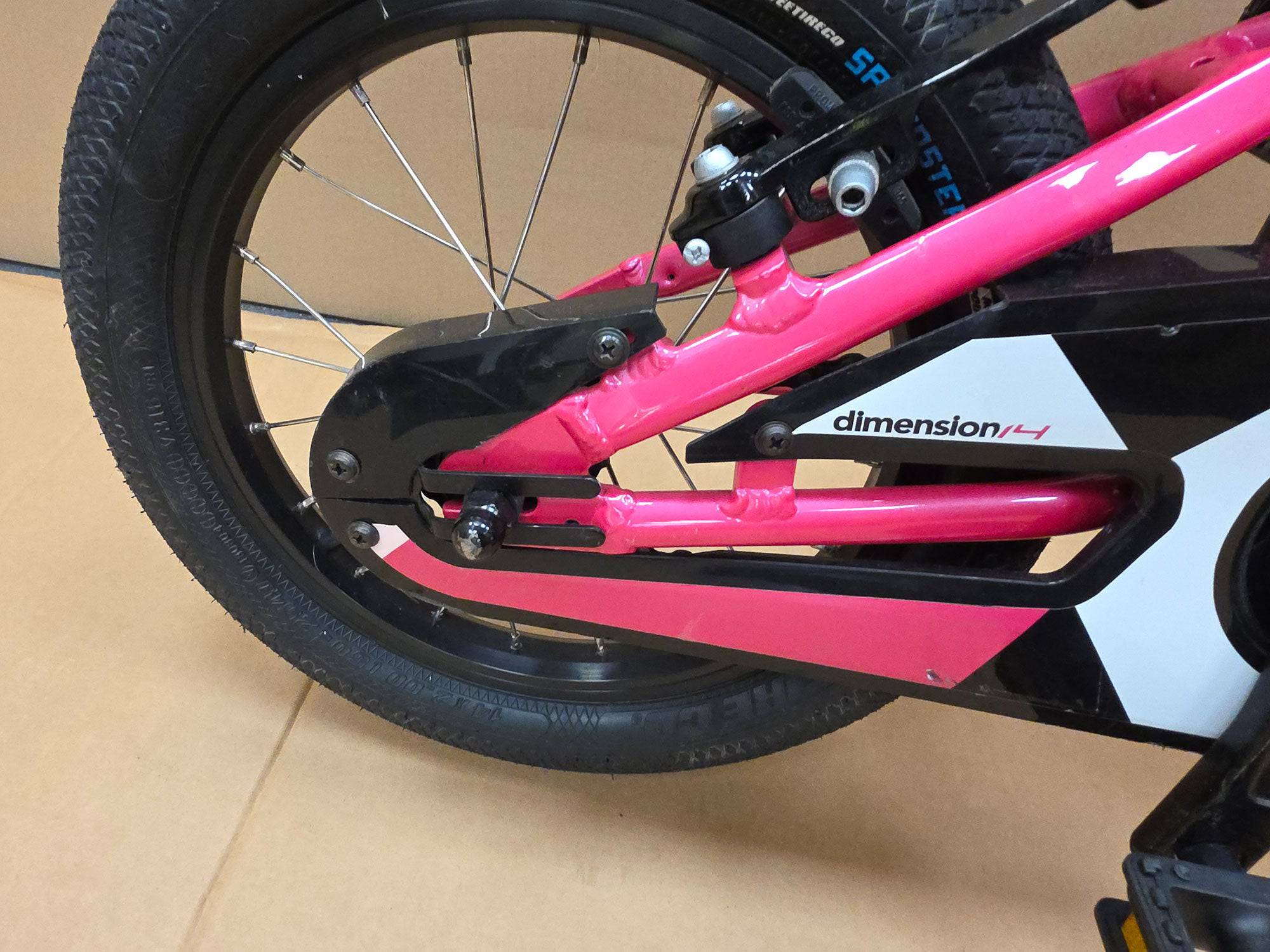 Pink Ridgeback Kids Dimension 14-inch beginner bike with training wheels, perfect for young children learning to ride.