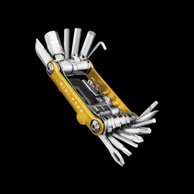 Topeak Mini PT30 30-function bike multi-tool with tubeless tyre repair kit, displayed on a workshop workbench.