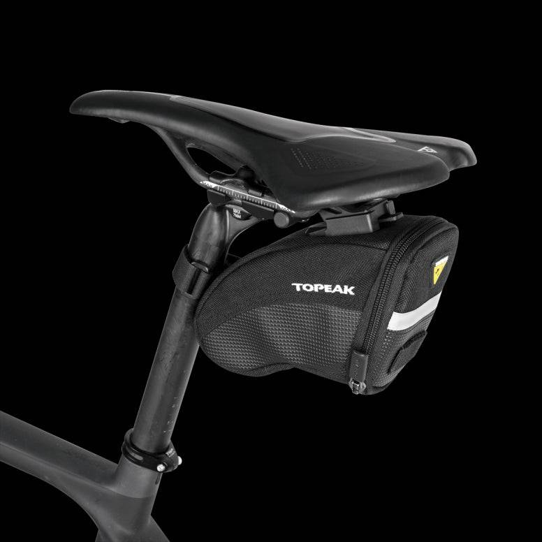 Topeak Aero Wedge Quickclick bike seat pack with pump holder and reflective strip, mounted under bike saddle for accessories storage.