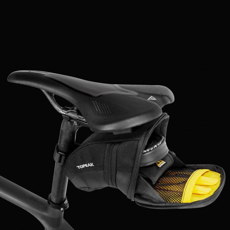 Topeak Aero Wedge Quickclick bike seat pack with pump holder and reflective strip attached to saddle for cycling accessories.