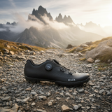 Black cycling shoe on a rocky trail with mountainous landscape