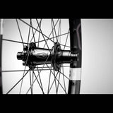 Crankbrothers Synthesis DH11 carbon rear wheel for downhill mountain biking, tubeless-ready, with black and red design and spokes.