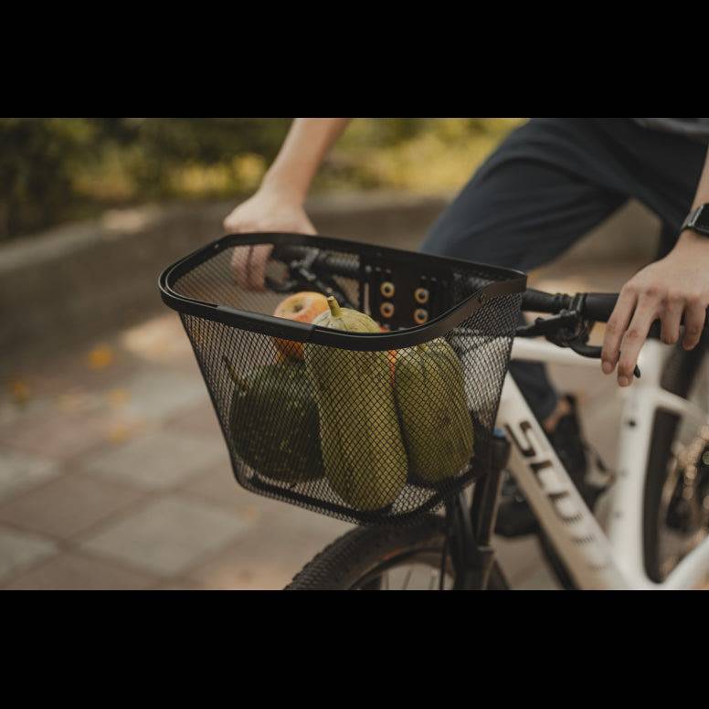 Black Topeak Urban Basket with QuickClick® system mounted on a bike handlebar for easy attachment and transport.