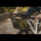 Black Topeak Urban Basket with QuickClick® system mounted on a bike handlebar for easy attachment and transport.