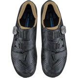 Shimano RX6W women's gravel cycling shoes with BOA dial and TPU lugs, shown in a natural outdoor setting.