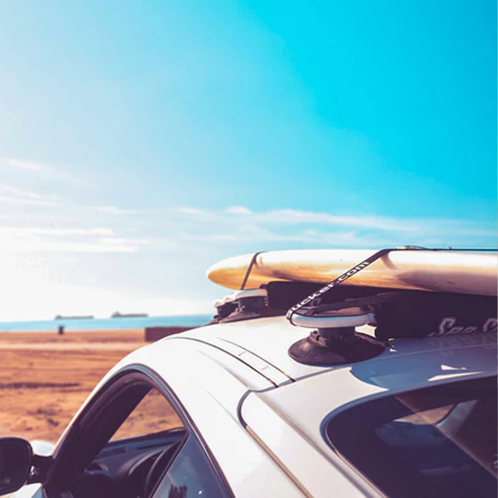 SeaSucker board rack with vacuum mounts attached to car roof, designed for surf and paddle boards, accessories for secure transport.