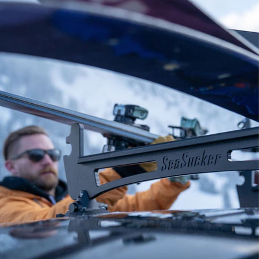 SeaSucker Classic Ski Rack vacuum mount holding four pairs of skis and snowboards, installed on a vehicle for outdoor winter sports.