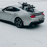 SeaSucker Classic Ski Rack vacuum mount holding four sets of skis and snowboards on a vehicle roof in a lifestyle setting.
