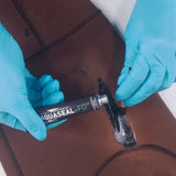 Gear Aid Aquasure FD waterproof urethane adhesive for outdoor gear repair, shown on clothing item in the image.
