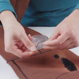 Gear Aid Aquasure FD waterproof urethane adhesive applied to outdoor clothing for waterproof gear repair.
