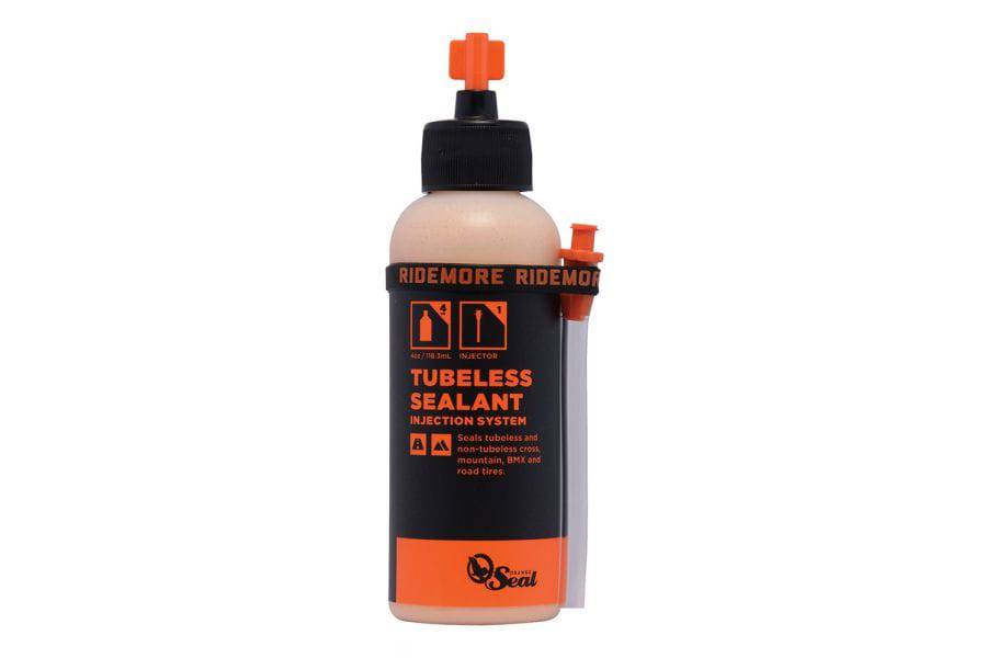 Orange Seal tubeless sealant refill for bike tires, shown in a container with orange-colored liquid for puncture protection.