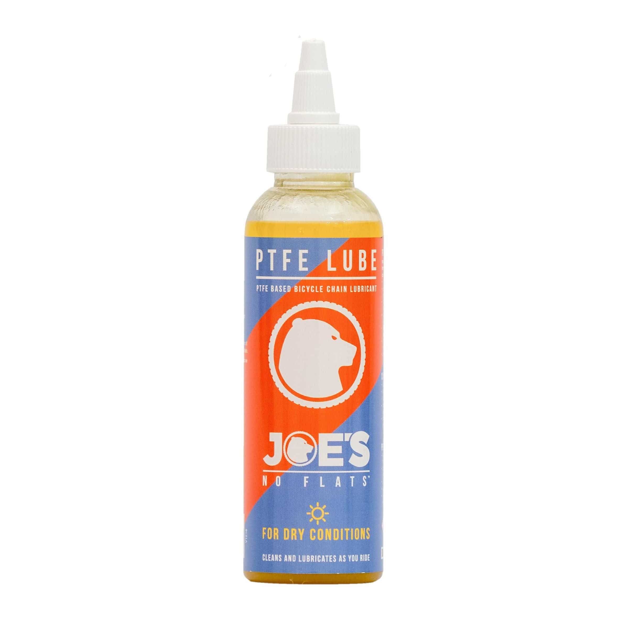 Joe's No Flats PTFE Dry Lube applied to a bicycle chain and drivetrain in a workshop setting.