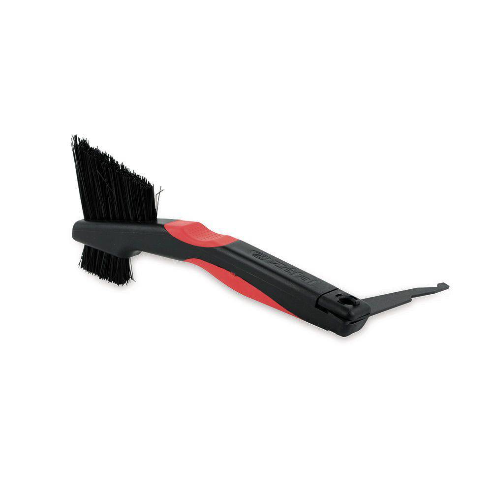 Zefal Clean Brush 3-in-1 bike cleaning tool for chains, freewheels, and derailleurs, shown in a workshop setting.