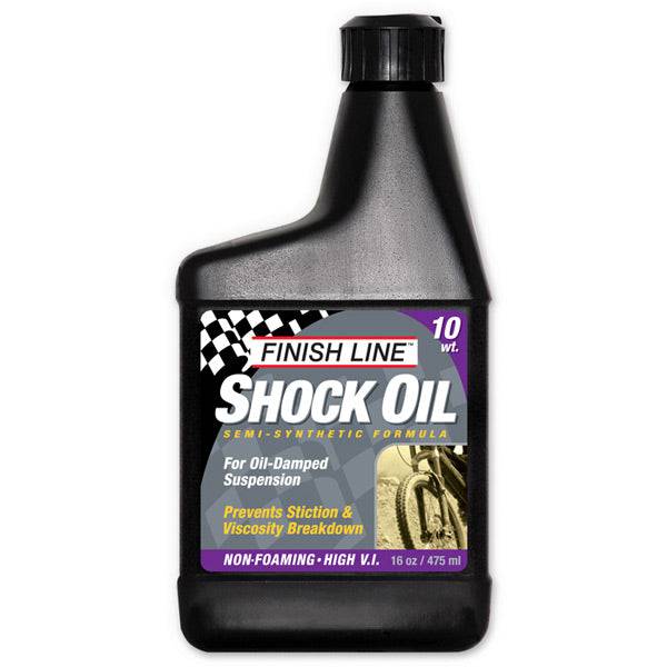 Finish Line Shock Oil 10 wt 16 oz bottle for bike suspension forks, shown in workshop setting with labeled packaging.