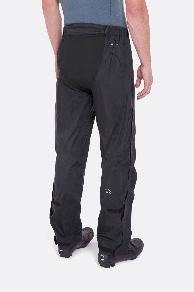Rab Cinder Downpour Light waterproof cycling pants in anthracite with articulated knees and side zips, shown from the back.