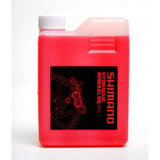 Shimano Mineral Oil Hydraulic Brake Fluid 1L in red for disc brake maintenance, shown in a workshop setting.